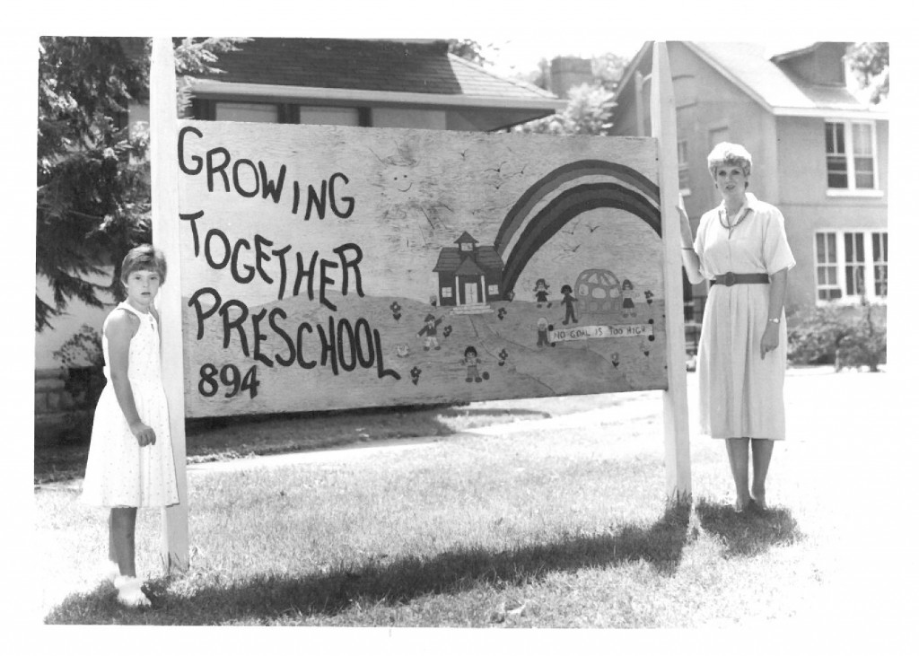 Leeann and her mother, Betsy, pose for a picture by the original Growing Together Preschool sign.